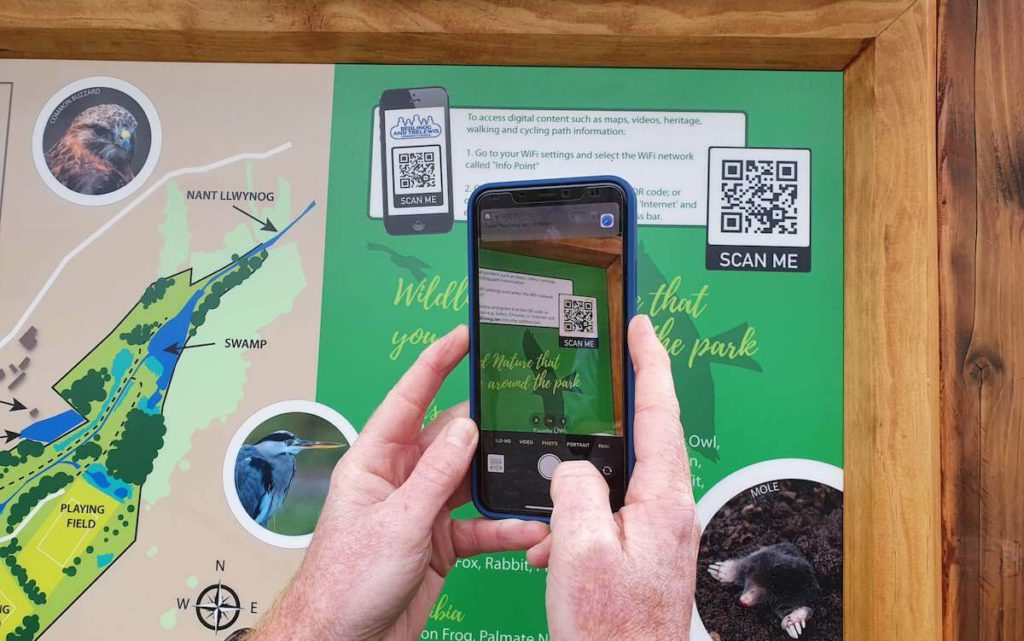 phone held up to qr code on bedlinog digital sign to access Info Point content