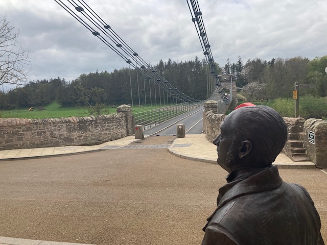 statue of engineer in front of the suspension bridge