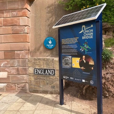 info point solar in a custom panel, with solar panels on top, standing in front of a wall